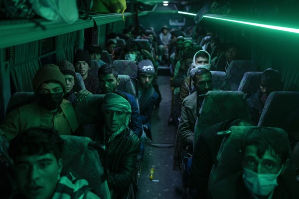 Afghan men sit in a bus ahead of a 300-mile trip south to Nimrooz near the Iranian border, Herat, Afghanistan, Nov. 22, 2021 (AP photo by Petros Giannakouris).
