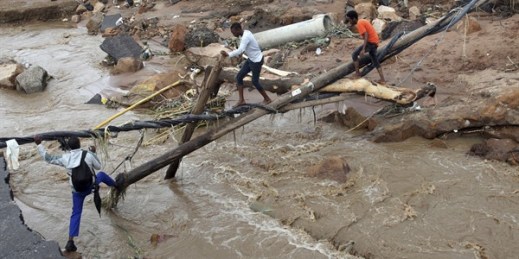 People walk across a makeshift bridge over a river, after a bridge was swept away in Ntuzuma, outside Durban, South Africa, April 12, 2022. (AP photo).