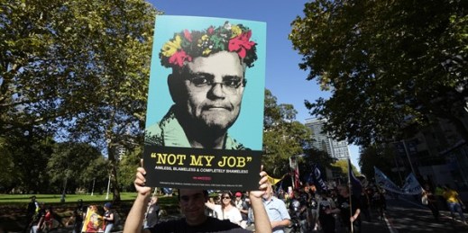 A man holds a placard mocking Australian Prime Minister Scott Morrison during the May Day rally in Sydney, May 1, 2022 (AP photo by Rick Rycroft).