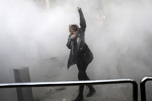 A university student attends a protest inside Tehran University while a smoke grenade is thrown by Iranian police, in Tehran, Iran, Dec. 30, 2017 (AP photo).