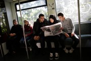 Syrian refugees sit in a train and read a local newspaper with special pages in Arabic for refugees, Berlin, Sept. 9, 2015.