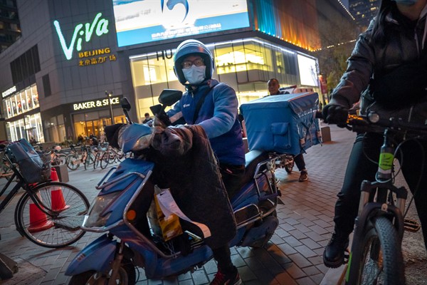 A delivery driver wearing a face mask to protect against the coronavirus waits at an intersection in Beijing, Nov. 26, 2020 (AP photo by Mark Schiefelbein).