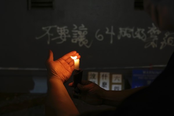 A protester lights candles to mark the anniversary of the 1989 military crackdown on the Tiananmen Square protests, outside the Victoria Park in Hong Kong, June 4, 2021 (AP photo by Kin Cheung).