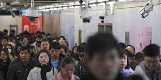 Commuters walk by surveillance cameras installed at a walkway in between two subway stations in Beijing, Feb. 26, 2019 (AP photo by Andy Wong).