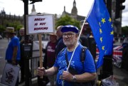A man holds a placard and an EU flag outside the Houses of Parliament, in London, July 6, 2022 (AP photo by Matt Dunham).