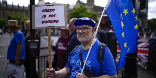A man holds a placard and an EU flag outside the Houses of Parliament, in London, July 6, 2022 (AP photo by Matt Dunham).