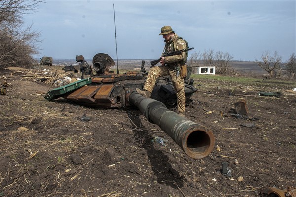 A Ukrainian serviceman steps on the barrel of a destroyed tank near the village of Malaya Rohan, Ukraine, April 1, 2022 (AP photo by Andrew Marienko).