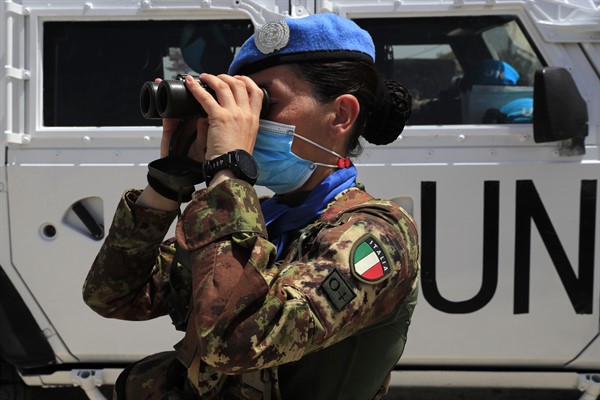 An Italian U.N. peacekeeping soldier looks through binoculars on a road that leads to a U.N. post along the Lebanese-Israeli border, in Naqoura, Lebanon, May 4, 2021 (AP photo by Hussein Malla).