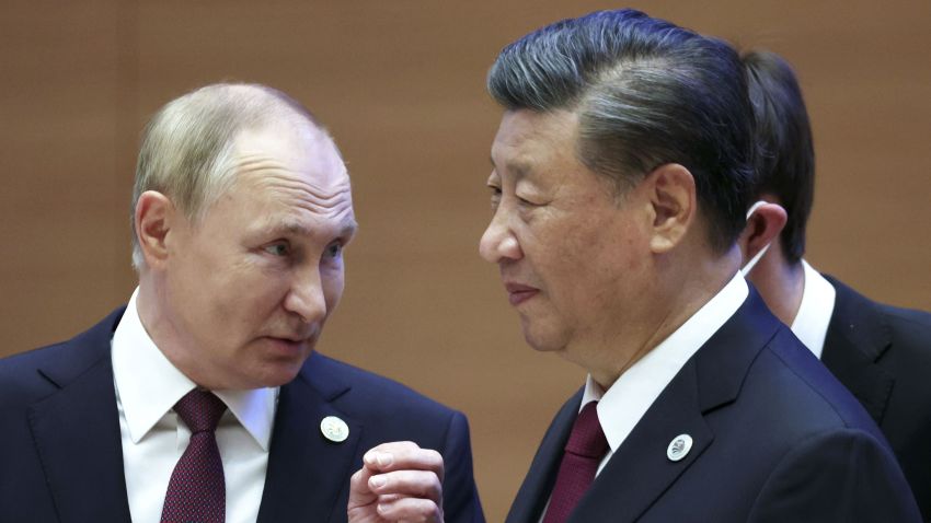 Russian President Vladimir Putin gestures while speaking to Chinese President Xi Jinping.