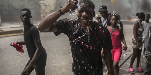 A protester affected by tear gas fired by police splashes water on his face, during a protest in Haiti.