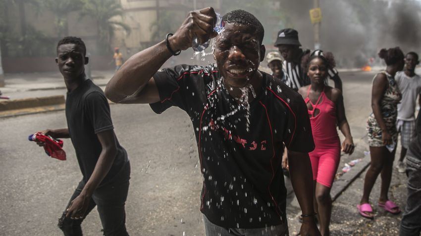A protester affected by tear gas fired by police splashes water on his face, during a protest in Haiti.