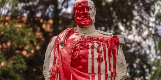 A statue of a colonial general covered in blood, symbolizing the movement for reparations and the dark legacy of colonialism by countries in Europe, Britain, and the US