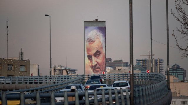 Vehicles drive past a giant portrait of Gen. Qasem Soleimani in downtown Tehran