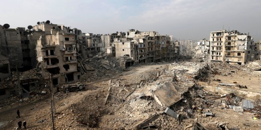 People walk through mounds of rubble that used to be high-rise apartment buildings in Aleppo, Syria.