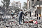 Palestinians walk outside buildings destroyed in the Israeli bombardment on al-Zahra, on the outskirts of Gaza City, Oct. 20, 2023.