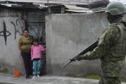 A soldier walks past residents in Ecuador.