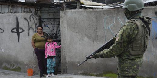 A soldier walks past residents in Ecuador.