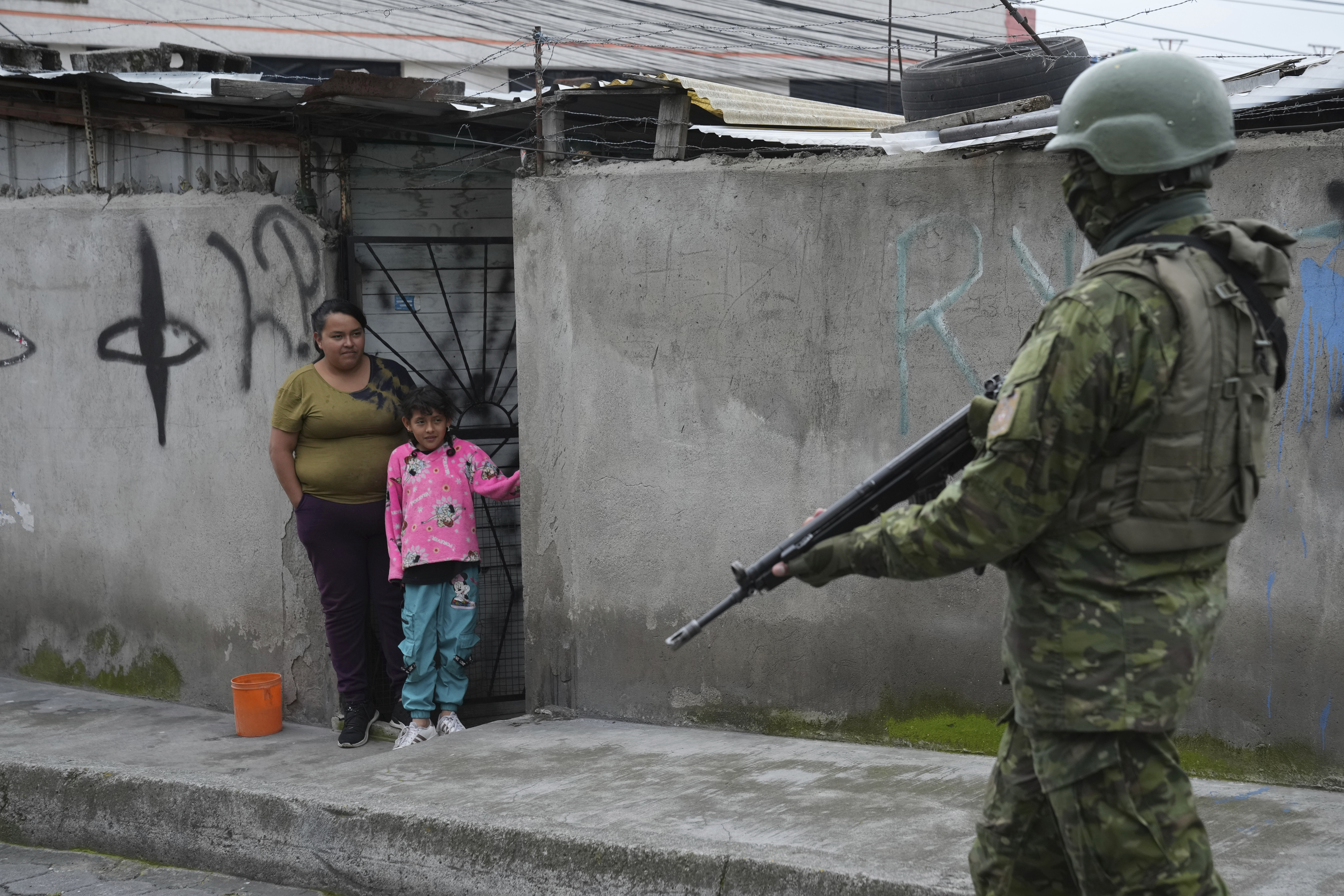A soldier walks past residents in Ecuador.