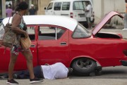 A man changes his car's tire in Havana, Cuba.