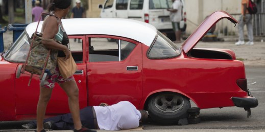 A man changes his car's tire in Havana, Cuba.