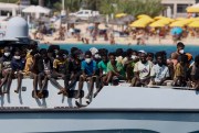 Migrants sit on the deck an Italian Coast Guard vessel.