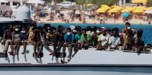 Migrants sit on the deck an Italian Coast Guard vessel.