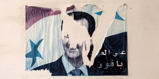 A torn poster showing the face of former Syrian dictator Bashar al-Assad.