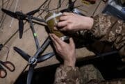 A Ukrainian soldier loads explosives onto a drone.