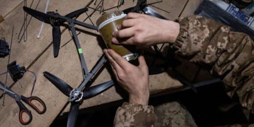 A Ukrainian soldier loads explosives onto a drone.