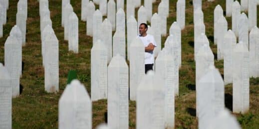 A man stands near a grave prior to the burial of newly identified victims of the Srebrenica genocide.