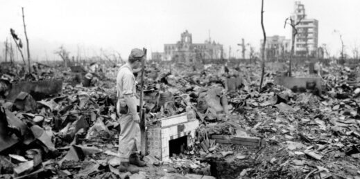 A man stands next to a tiled fireplace where a house once stood in Hiroshima.